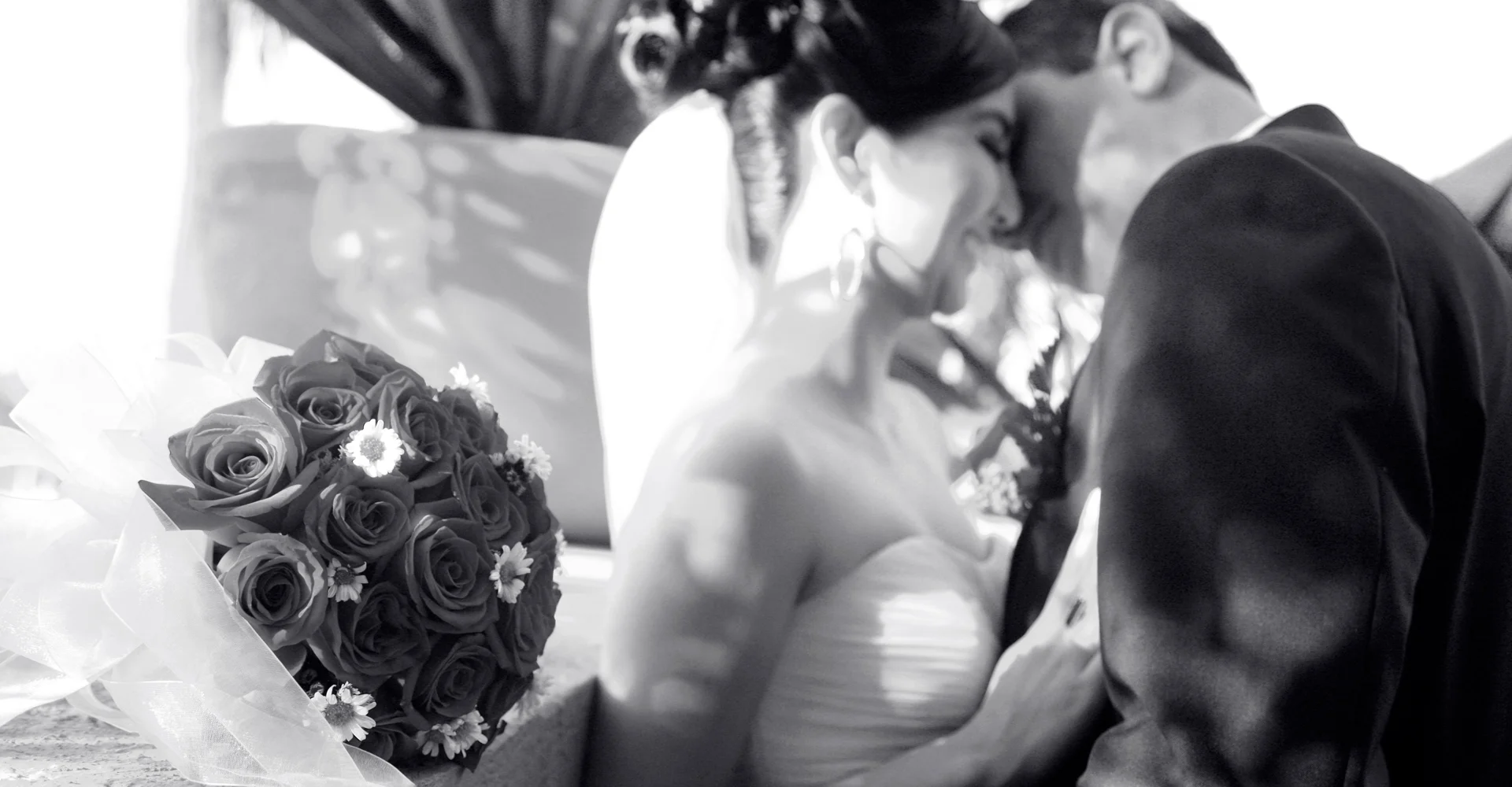 Novios frente a frente junto a un ramo de flores, en blanco y negro